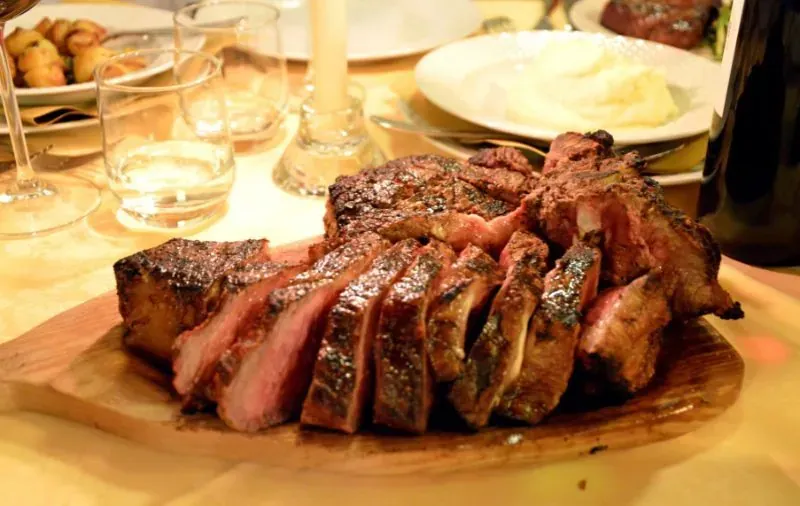 Sliced Bistecca alla Fiorentina steak served on a wooden board